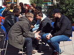 Menschen sitzen sich in zwei Reihen gegenüber und sprechen miteinander
