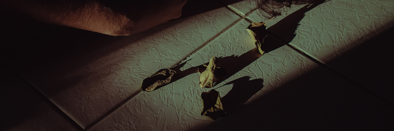 vertrocknete Rosenblätter liegen auf einem Fließenboden