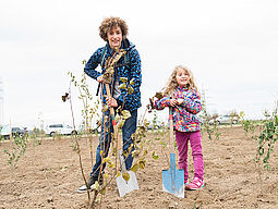 Ein Junge und ein Mädchen pflanzen einen Jungbaum.