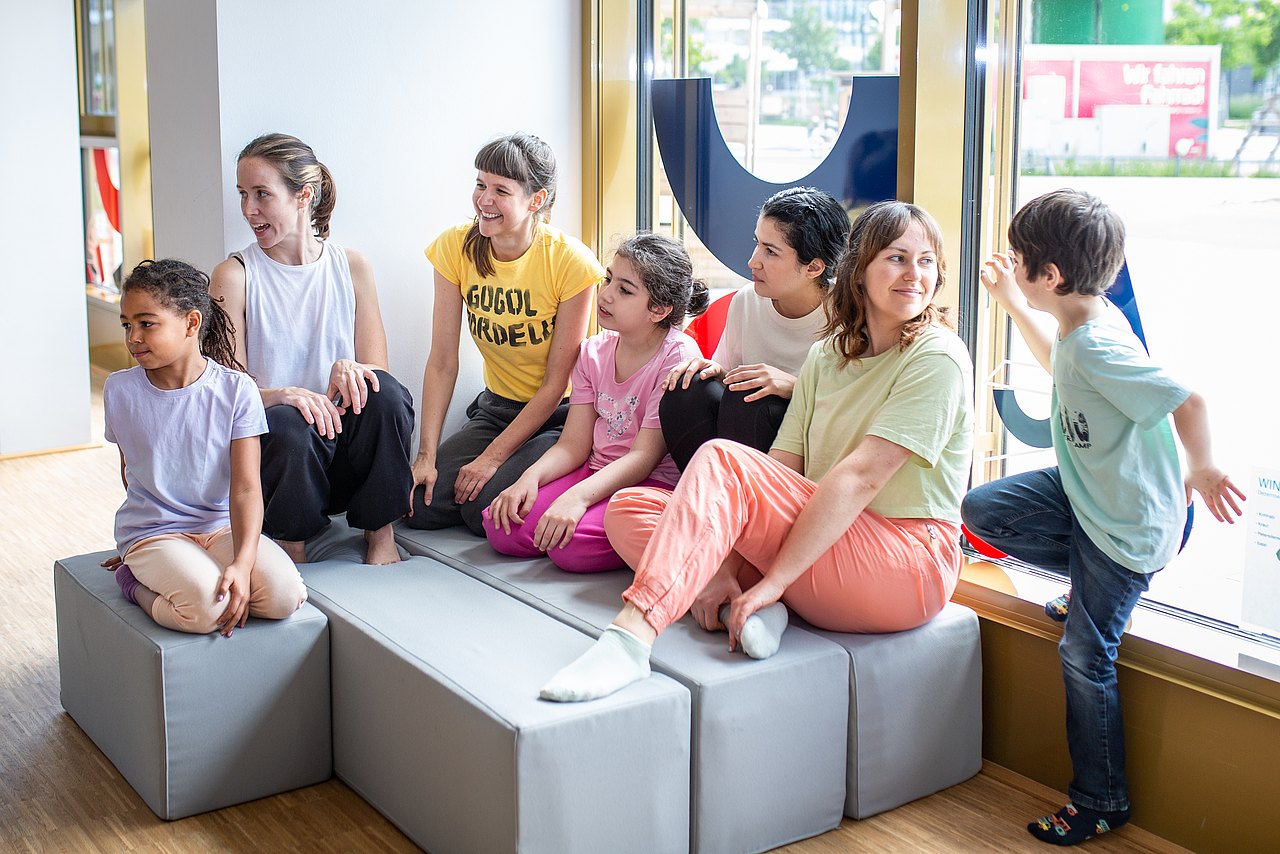WIENXTRA-Kinderaktiv: Sowieso! Tanzworkshop in der Stadtbox Kindergruppe sitzt in der WIENXTRA-Stadtbox auf Polsterelementen