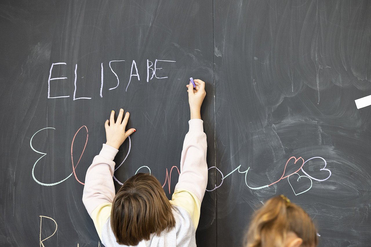 Schule Kind schreibt etwas auf eine Tafel