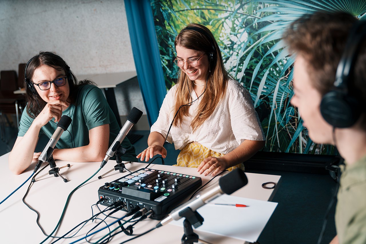 mz2025 x ste.krenn-11 Drei Jugendliche sitzen an einem Tisch mit Mikrofonen und einem Audio-Mischpult und nehmen gemeinsam einen Podcast auf..