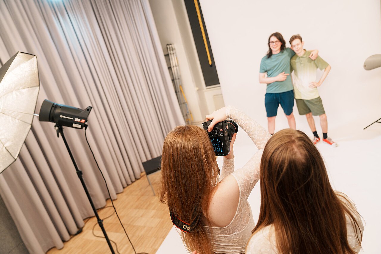 mz2025 x ste.krenn-103 Zwei Jugendliche werden von zwei anderen Jugendlichen vor weißem Hintergrund in einem Studio fotografiert.
