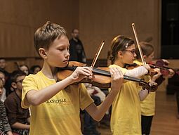 Singen Ein Schüler und eine Schülerin spielen Geige.