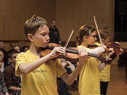 Ein Schüler und eine Schülerin spielen Geige.