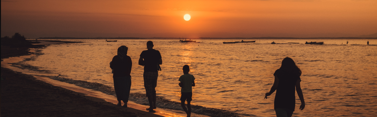 Eine Gruppe Menschen geht bei Sonnenuntergang am Meer spazieren