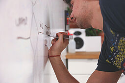 Junger Mann schreibt auf einem Whiteboard