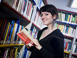 Frau liest ein Buch in der Bibliothek