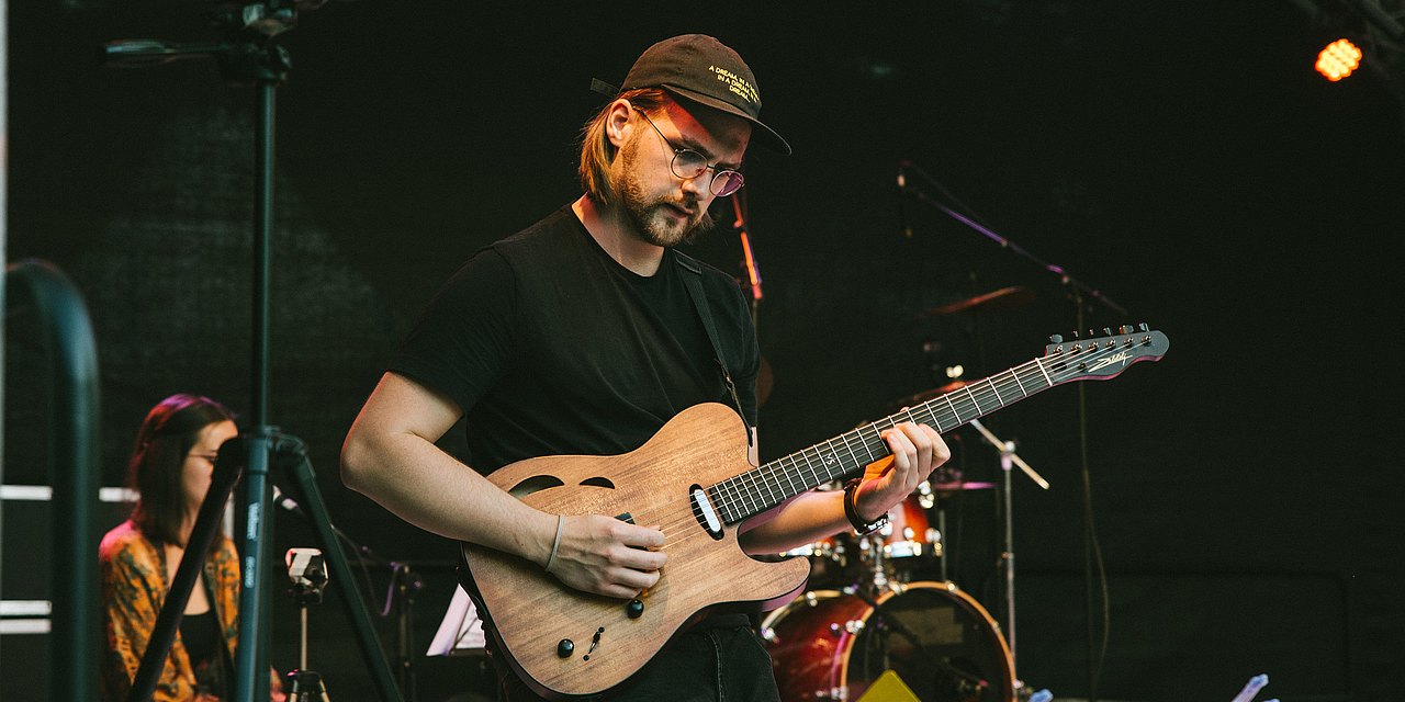 Eine Person spielt Gitarre auf der Bühne.