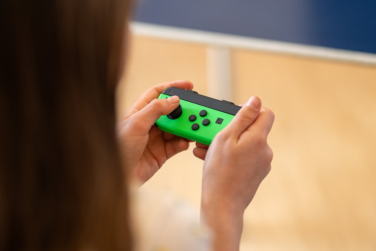 8132_© Barbara Mair Kopie Kind mit langen Haaren hält Joy-Con in der Hand