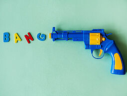 Blaue Spielzeugpistole mit BANG-Schriftzug vor Lauf