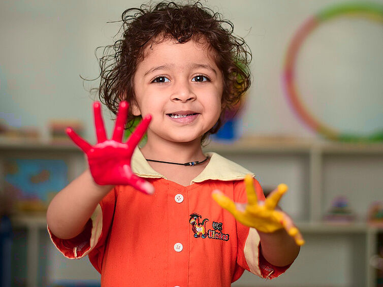 Kleinkind mit bunten Händen Kleinkind mit bunt bemalten Händen