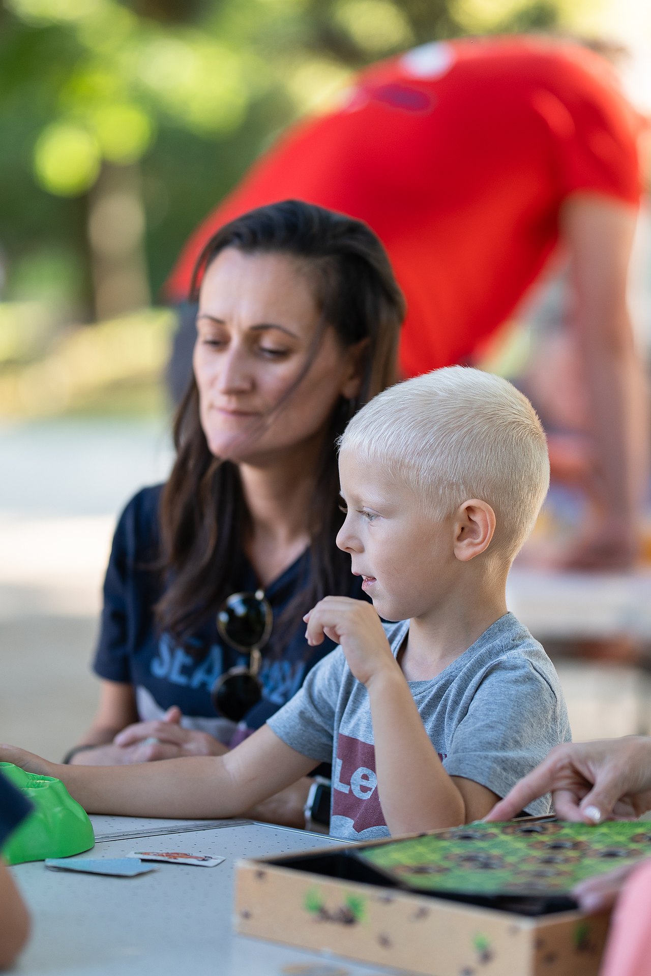 WIENXTRA_Spielebox_Kajetan_Koren_26082025_045 Frau und Kind an einem Spieltisch mit einem Brettspiel im Park