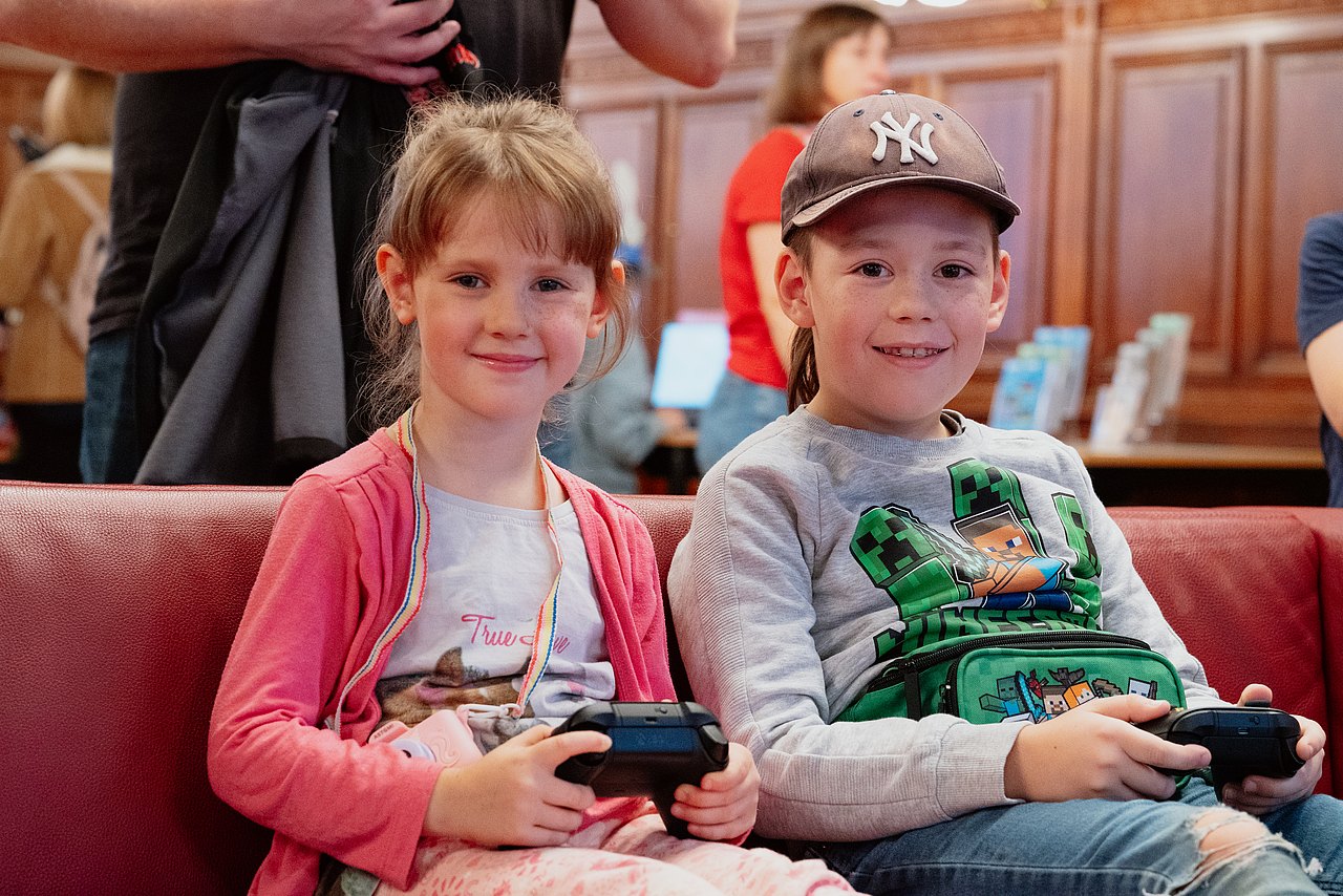 SpB_c_Kajetan_Koren_12102025_012 Zwei Kinder mit Controllern in der Hand lächeln in die Kamera