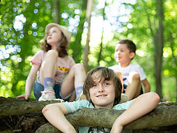 Abenteuer_Wald_2 Drei Kinder auf einem Baumstamm.