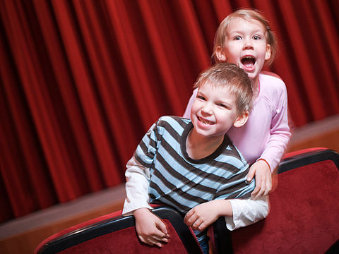 Publikum Bub und Maedchen lachend im Theaterraum