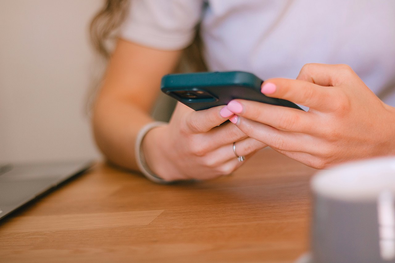 Nacktbilder Eine Person mit rosa Fingernägel benutzt ein Smartphone.