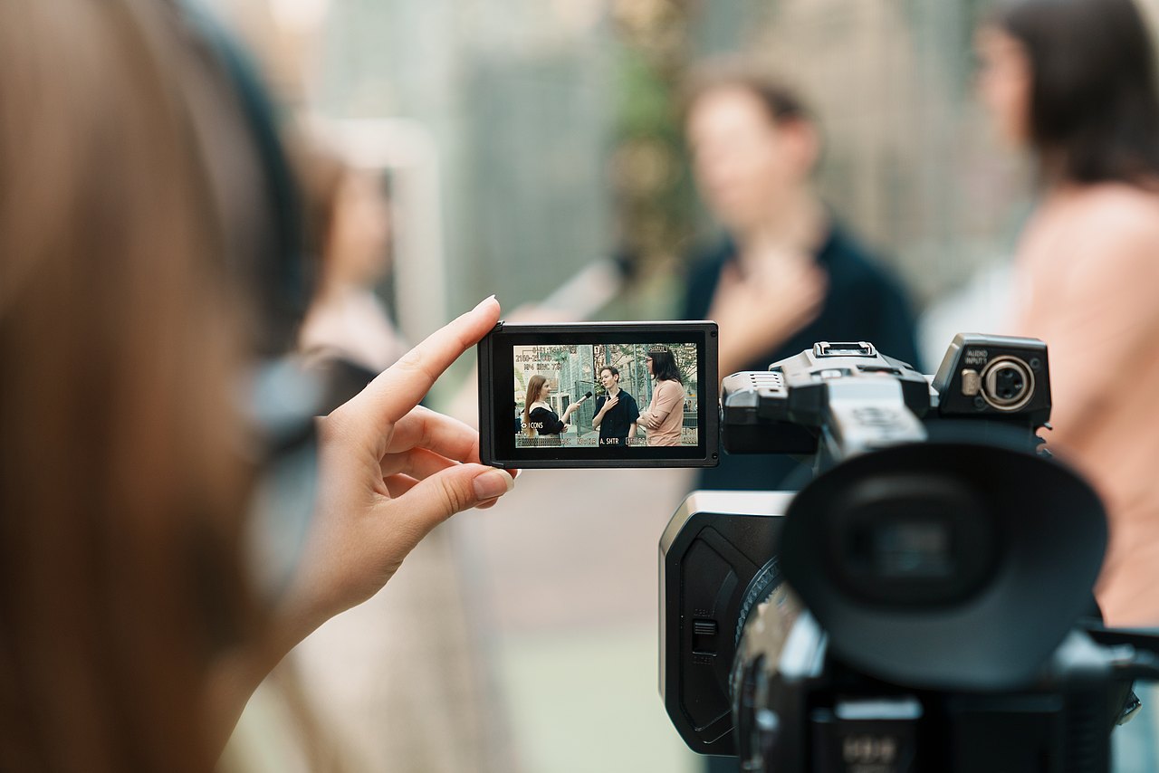 mz2025 x ste.krenn-186 Durch den Bildschirm einer Videokamera sieht man zwei Jugendliche, die ein Interview führen.