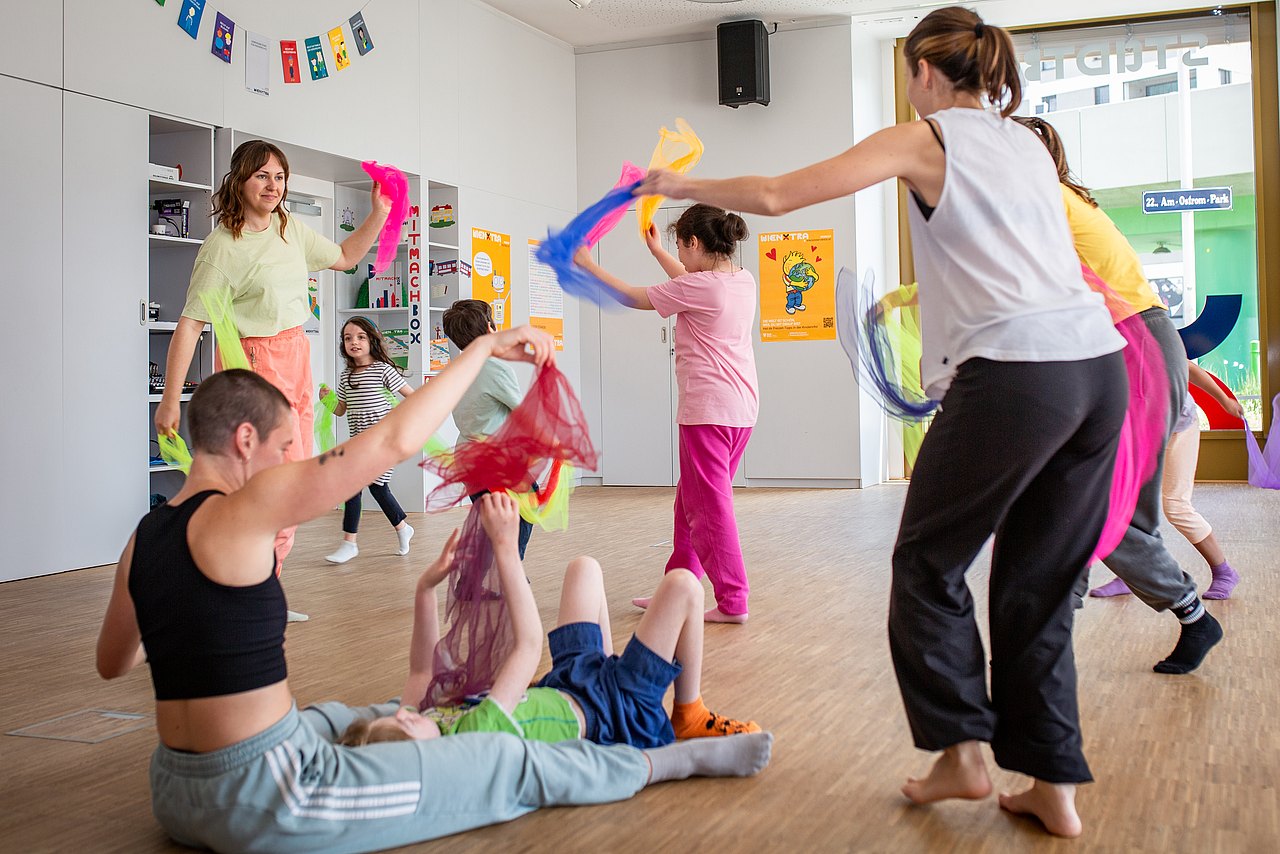 WIENXTRA-Kinderaktiv: Sowieso! Tanzworkshop in der Stadtbox mehrere Kinder tanzen mit Tüchern durch einen Raum