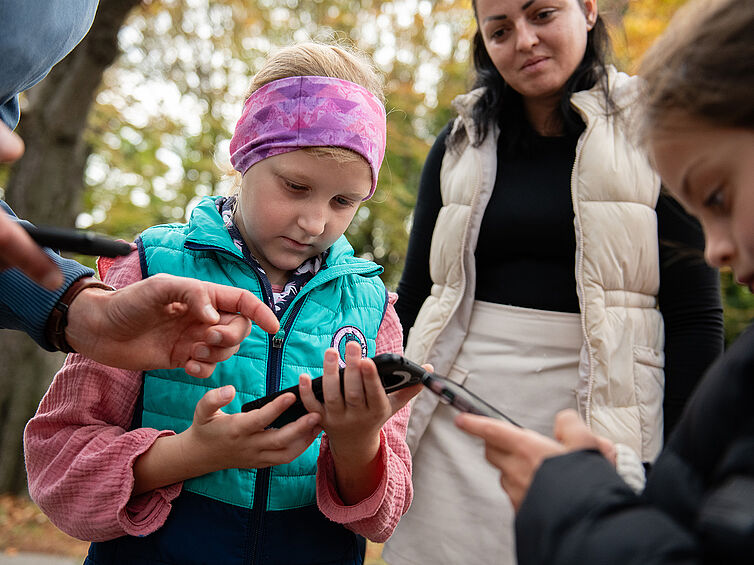 Kinder lesen eine Aufgabe am Handy.
