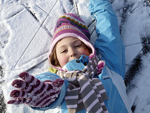 Winterkind Kind liegt im Schnee