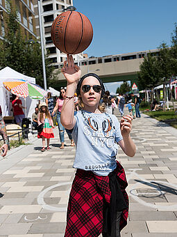 Ein Mädchen dreht einen Basketball auf dem Finger. 