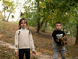 Herbst Zwei Kinder spielen mit Laub.