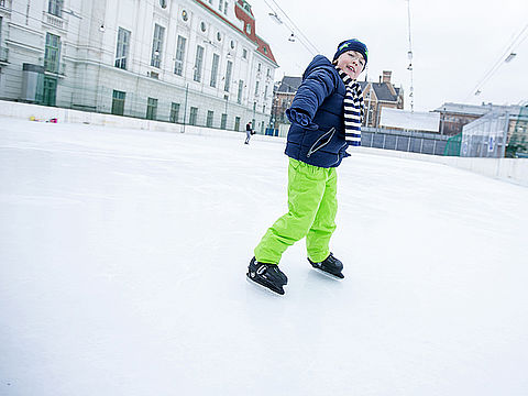Bub mit grüner Hose beim Eislaufen