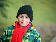 Bub im Herbst Bub mit Haube, Schal und Anorak in der Natur