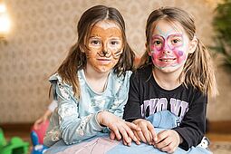 Osterferienspiel Zwei Mädchen, die eine als Tiger, die andere als Schmetterling geschminkt.