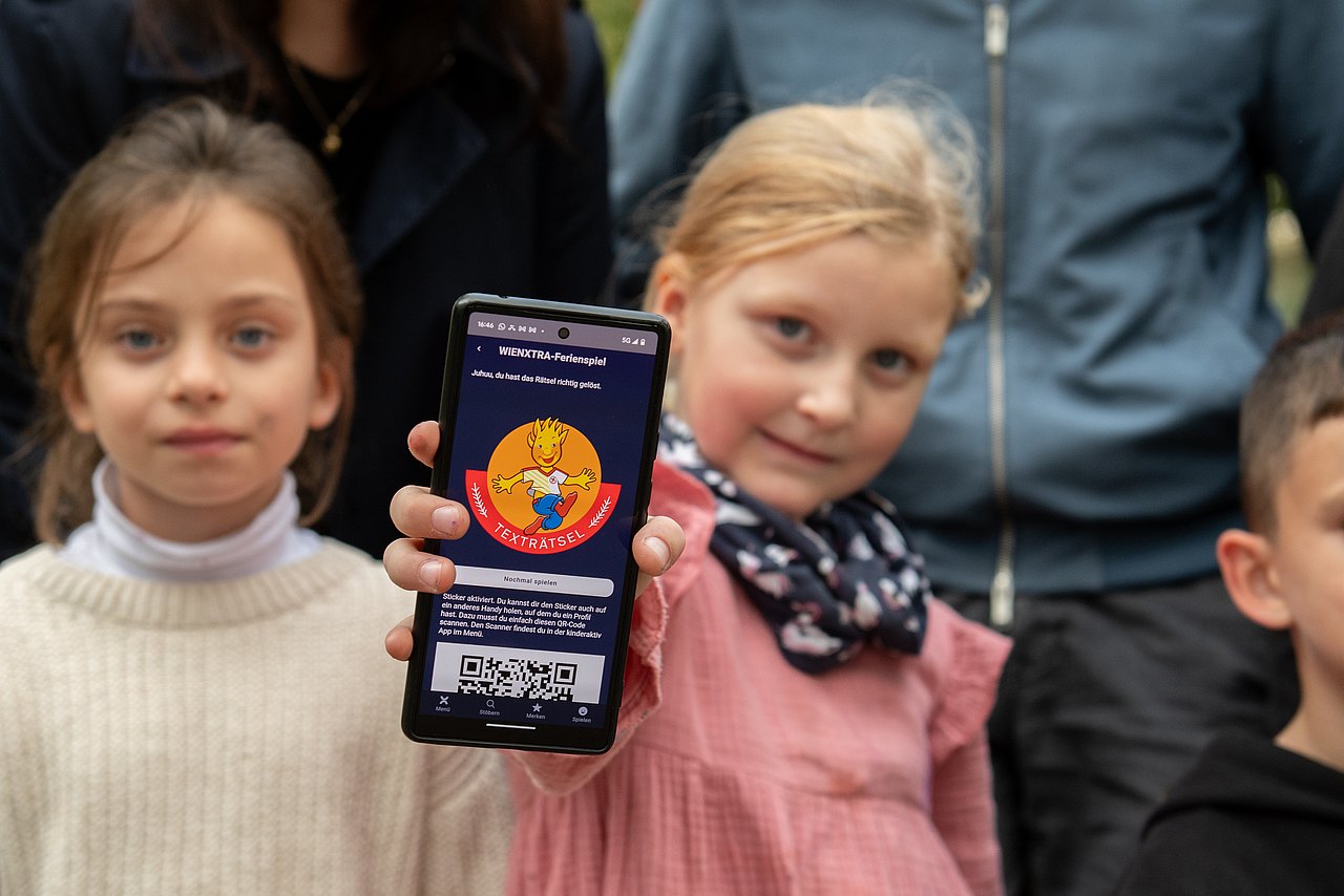 Rätselrallye_c_Liebentritt_072 mehrere Kinder, eines hält ein Smartphone mit einem Holli-Sticker