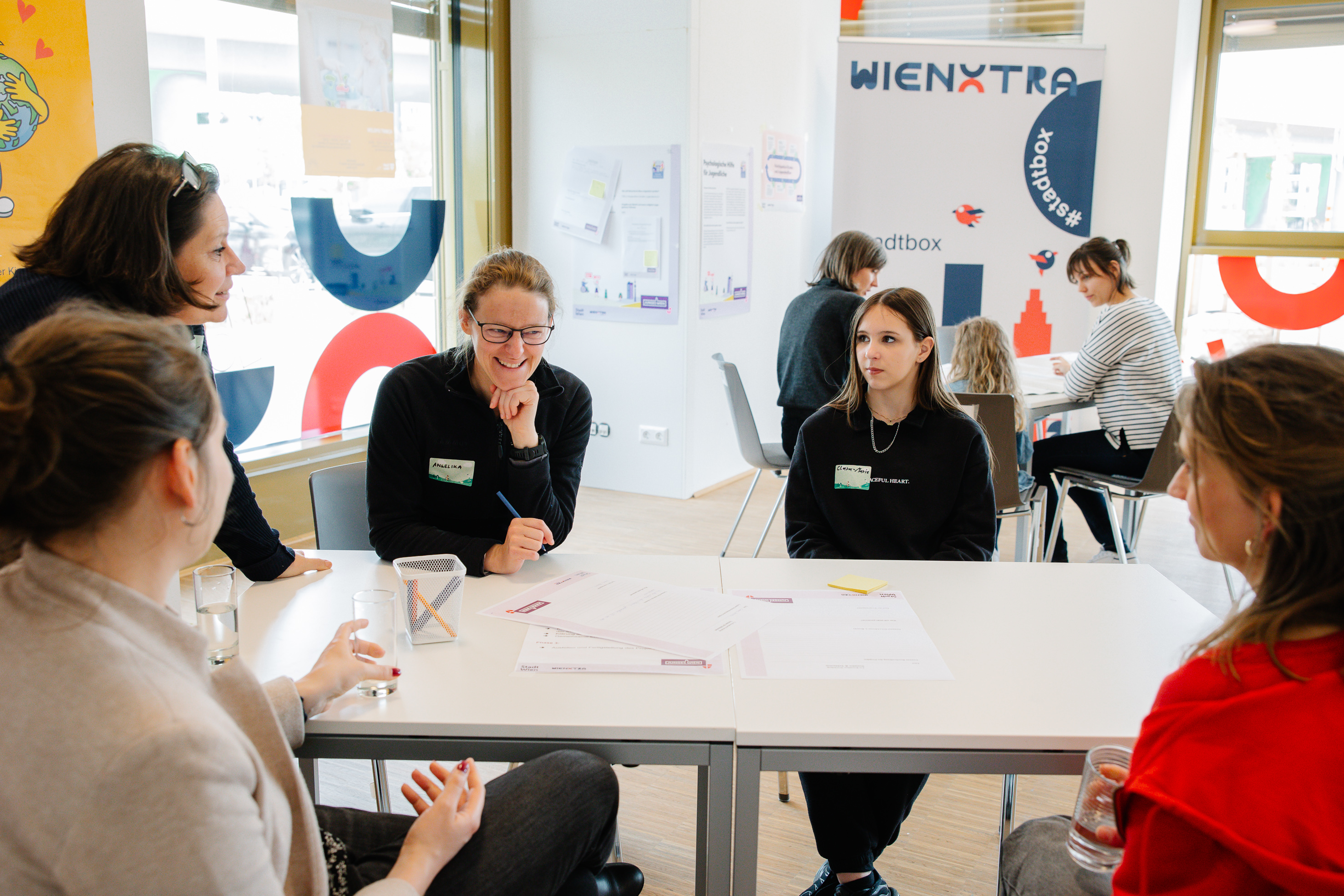 Junges Wien Personen sitzen an einem Tisch und besprechen ein Thema