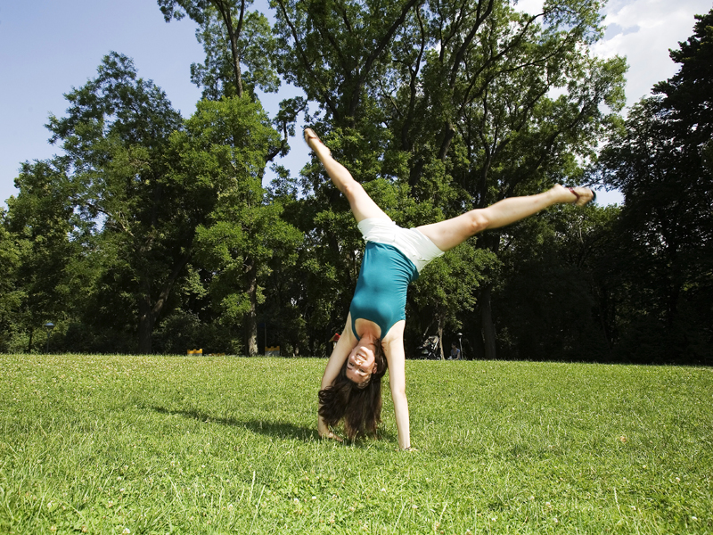 Mädchen macht Handstand auf der Wiese