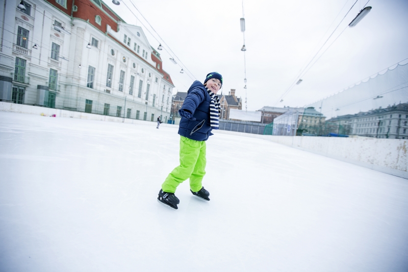 Ein Junge in neongrüner Skihose beim Eislaufen. 