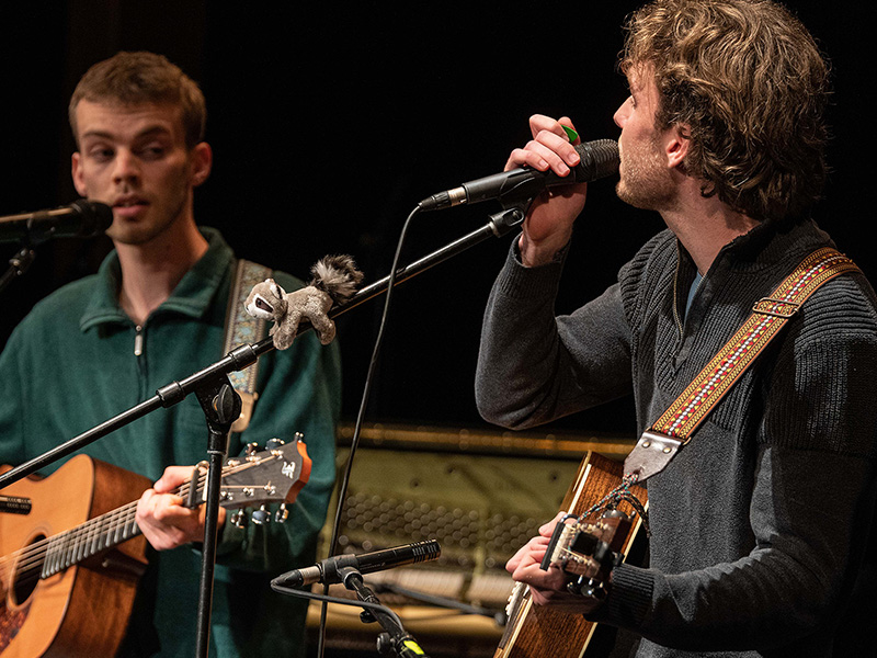 Zwei junge Musiker spielen Gitarre und singen.