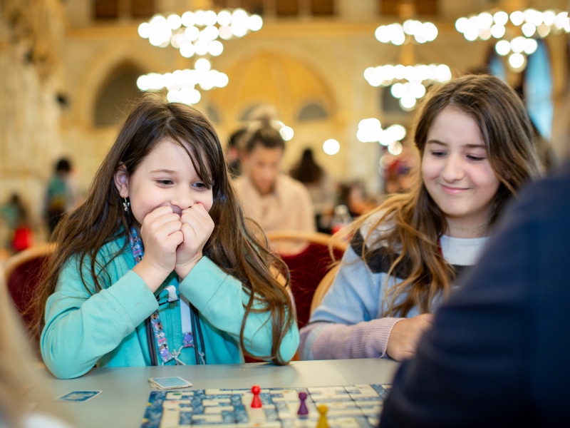 Zwei Mädchen spielen ganz aufgeregt ein Brettspiel.