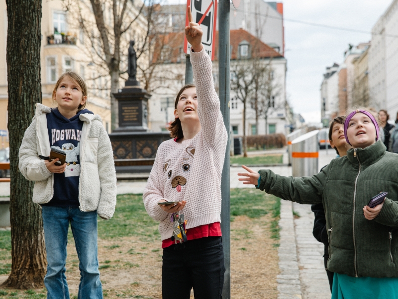 Eine Gruppe von Kindern sucht nach versteckten Hinweisen entlang der Rätselrallye.