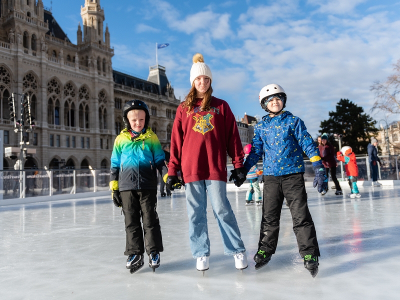 Semesterferien Drei Kinder sind am Eislaufplatz.