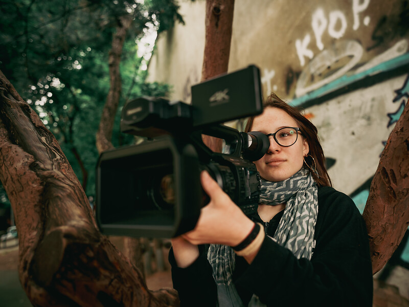 Junge Frau schaut durch eine Filmkamera.