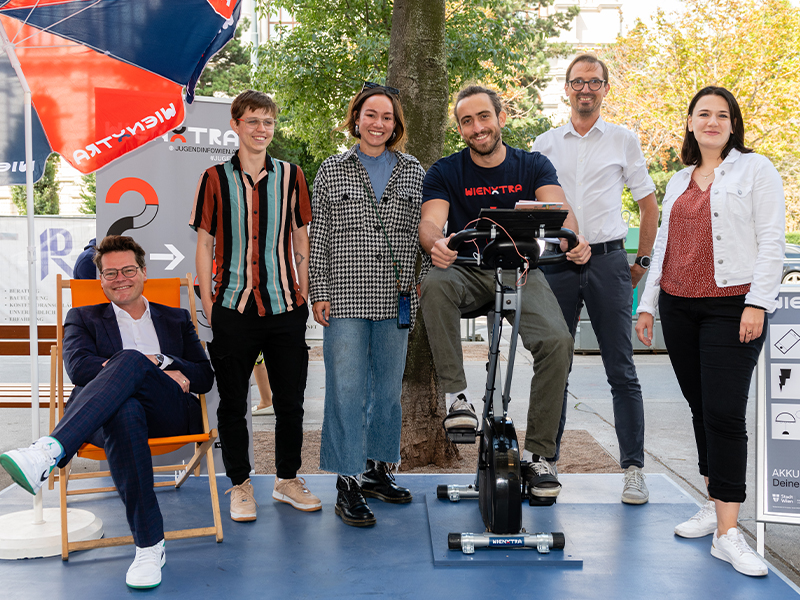 Akku Rad Grätzloase Personengruppe mit Standfahrrad